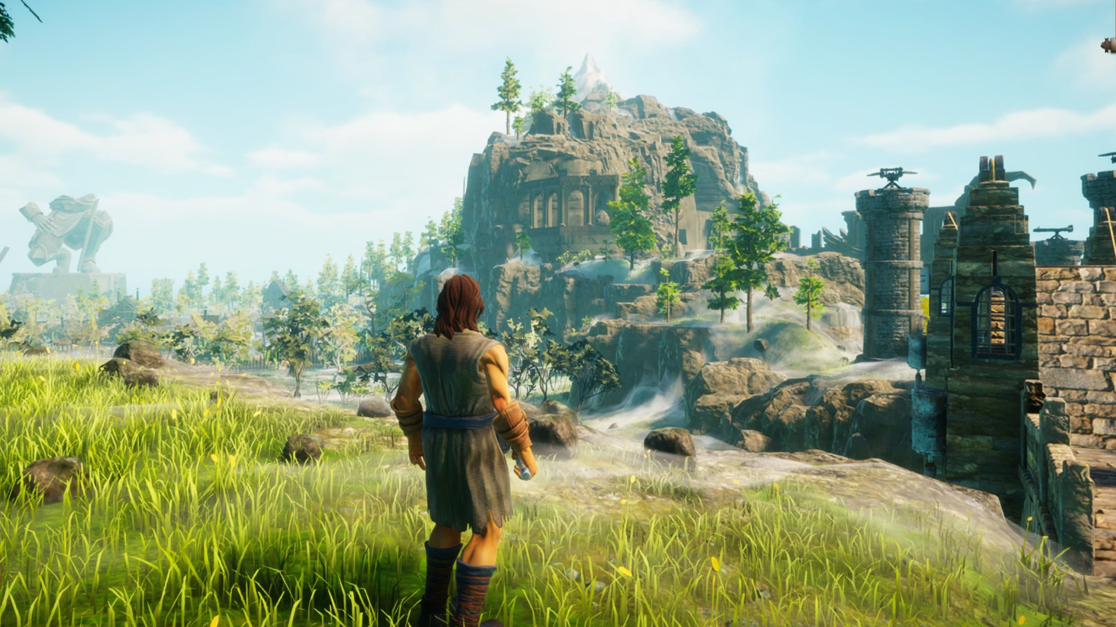 A man stands in a green field looking a a distant castle