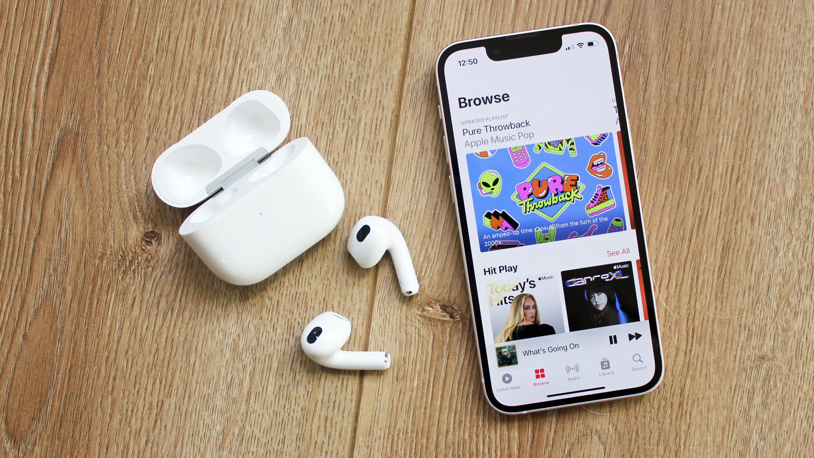 the airpods 3 next to an iphone 13 mini with apple music on the screen