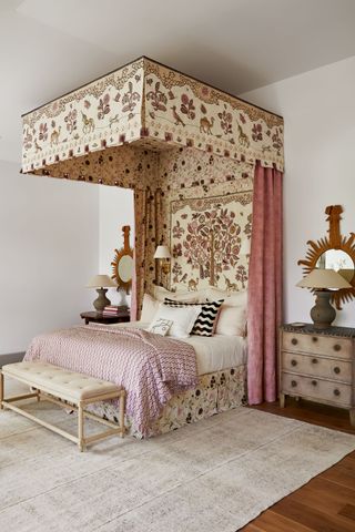 Pink and cream themed bedroom with tree tapestry above bed, orange sunshine mirrors