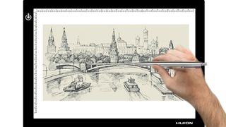 Hand tracing city scene onto paper using light pad