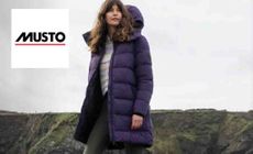 Musto logo placed over an image of a woman wearing a long puffer jacket in the coastal side