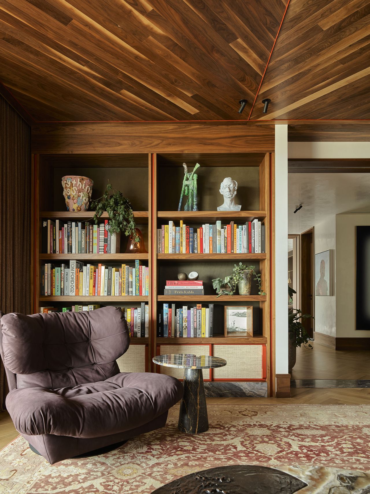 home library with wooden panelled ceilings, bookcase, patterned rug, and purple armchair