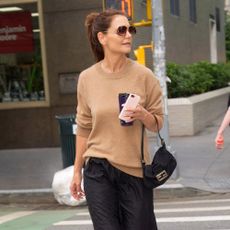 Katie Holmes wears a beige jumper with a midi skirt and tortoise loafers.