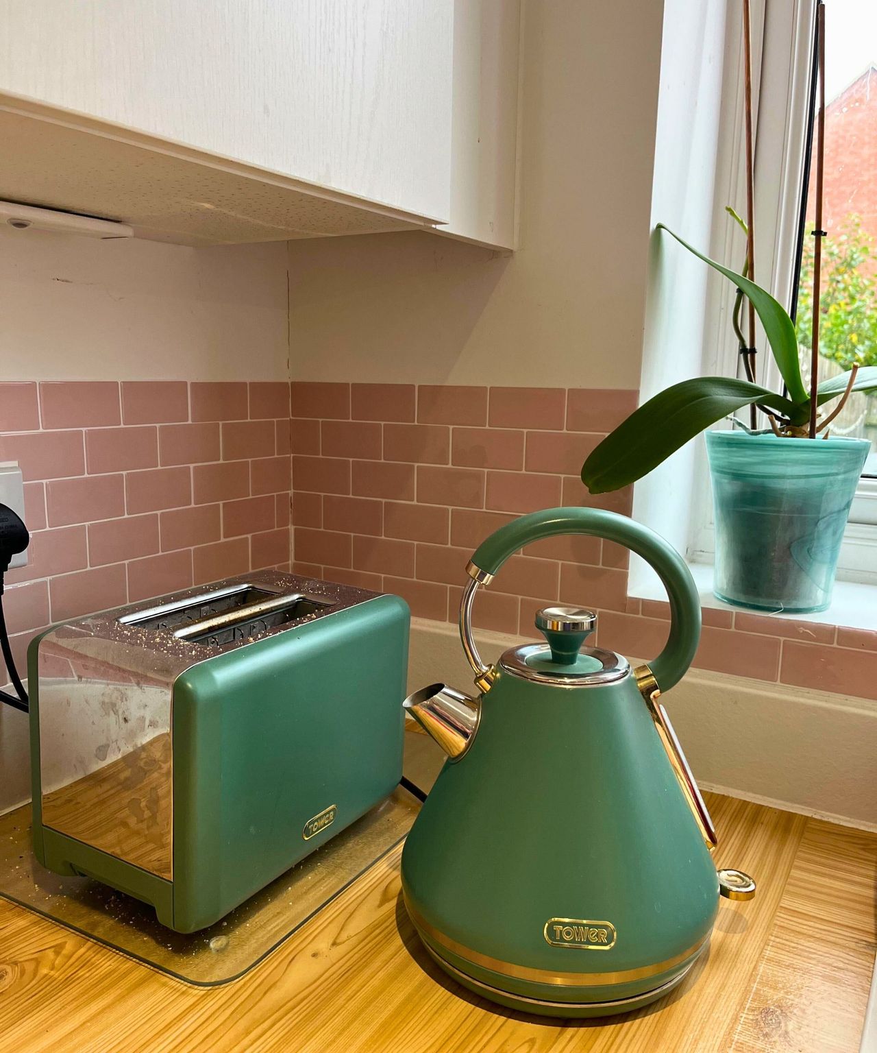 My sage green and stainless steel Tower toaster and kettle set on wooden worktop against pink subway tiled backsplash. The stainless steel is marked and grubby