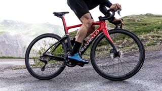 A black and red bike climbs an alpine hairpin