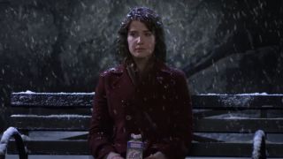 Cobie Smulders as Robin sitting on a bench in the snow drinking egg nog on How I Met Your Mother