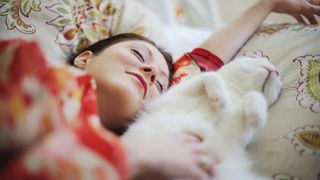 Sleeping owner with cat on the pillow