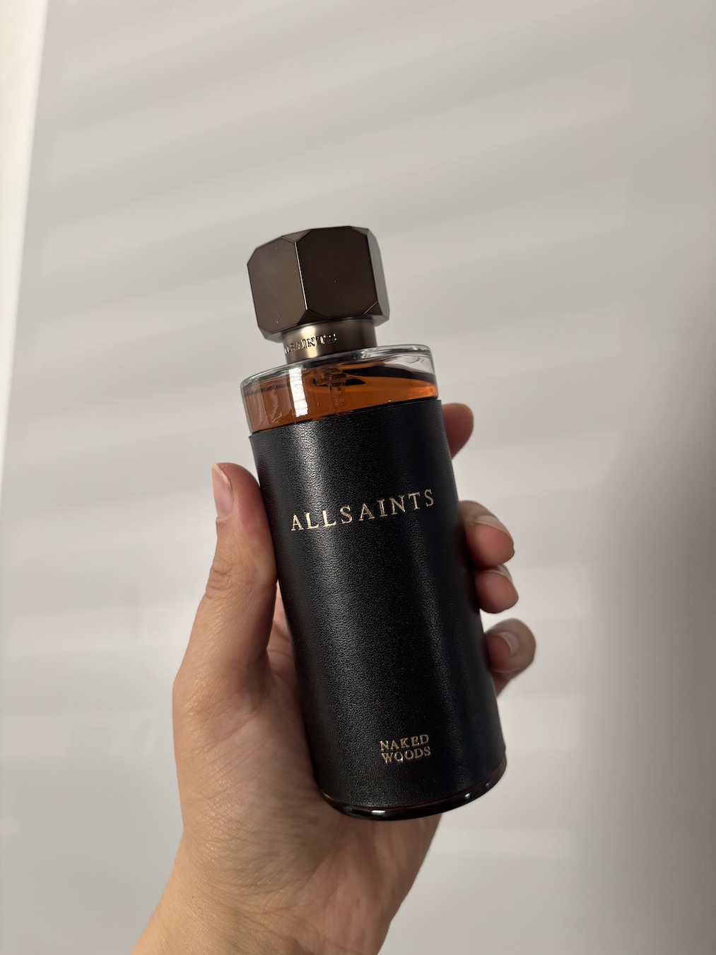 Mica Ricketts holding bottle of AllSaints Naked Woods perfume