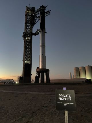 a giant rocket stands in after sunset. A private property sign stands in the foreground