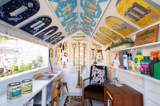 The interiors of the shed show white painted walls with colourful murals inside the the roof and walls as well as the award hanging on a shelf