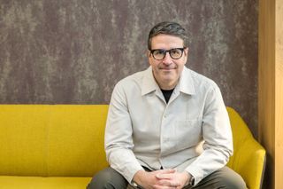 man with glasses and a pale shirt on a yellow sofa