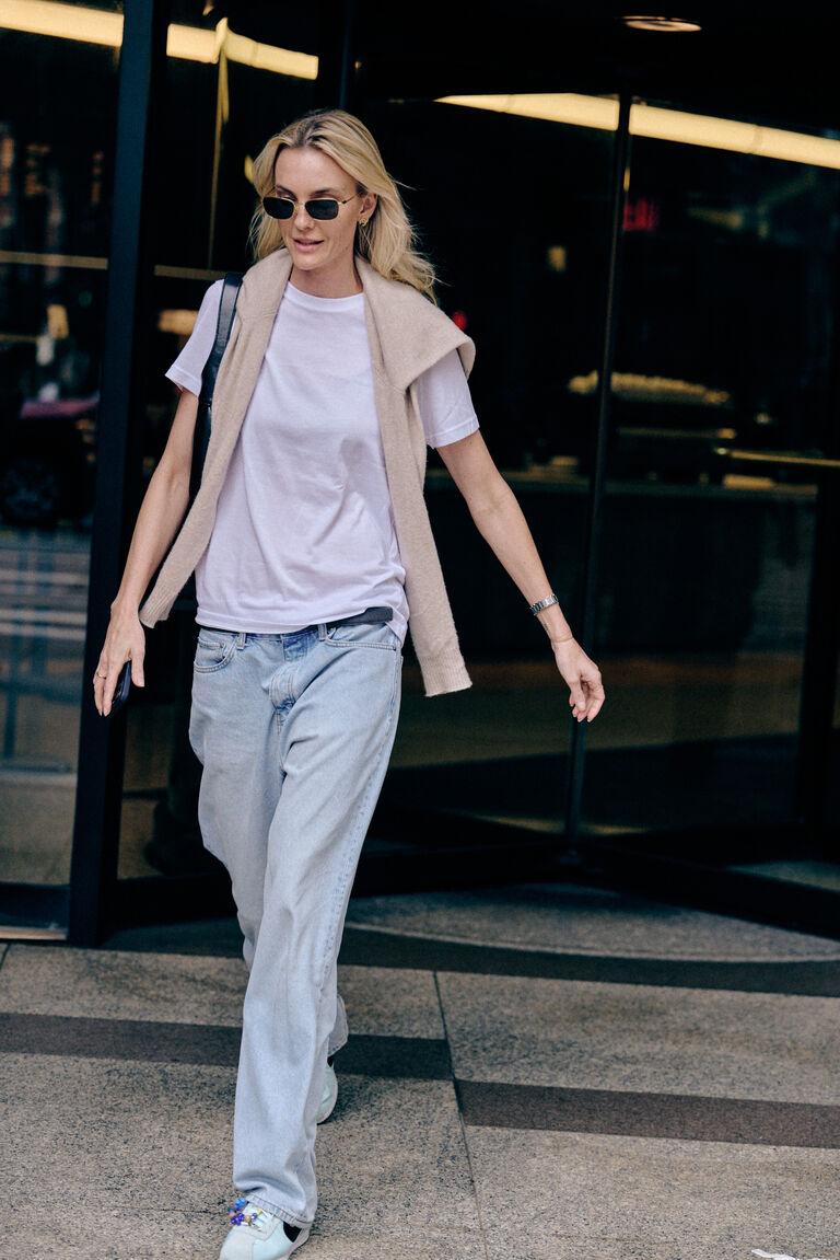 woman wearing jeans and a tee shirt with a sweater around her shoulders