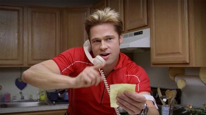 Brad Pitt holds a phone up to his face in a still from the movie Burn After Reading