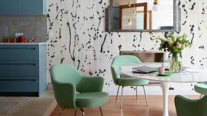 Open plan kitchen with dining area with blue wallpaper and green chairs