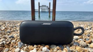Bose SoundLink Plus on Brighton Beach pebbles, with the old pier in the background 