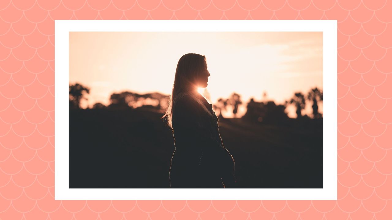 woman&#039;s silhouette as the sun sets on a salmon-colored background