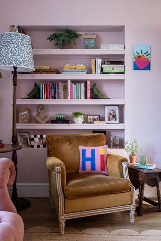 pink living room with shelves and armchair