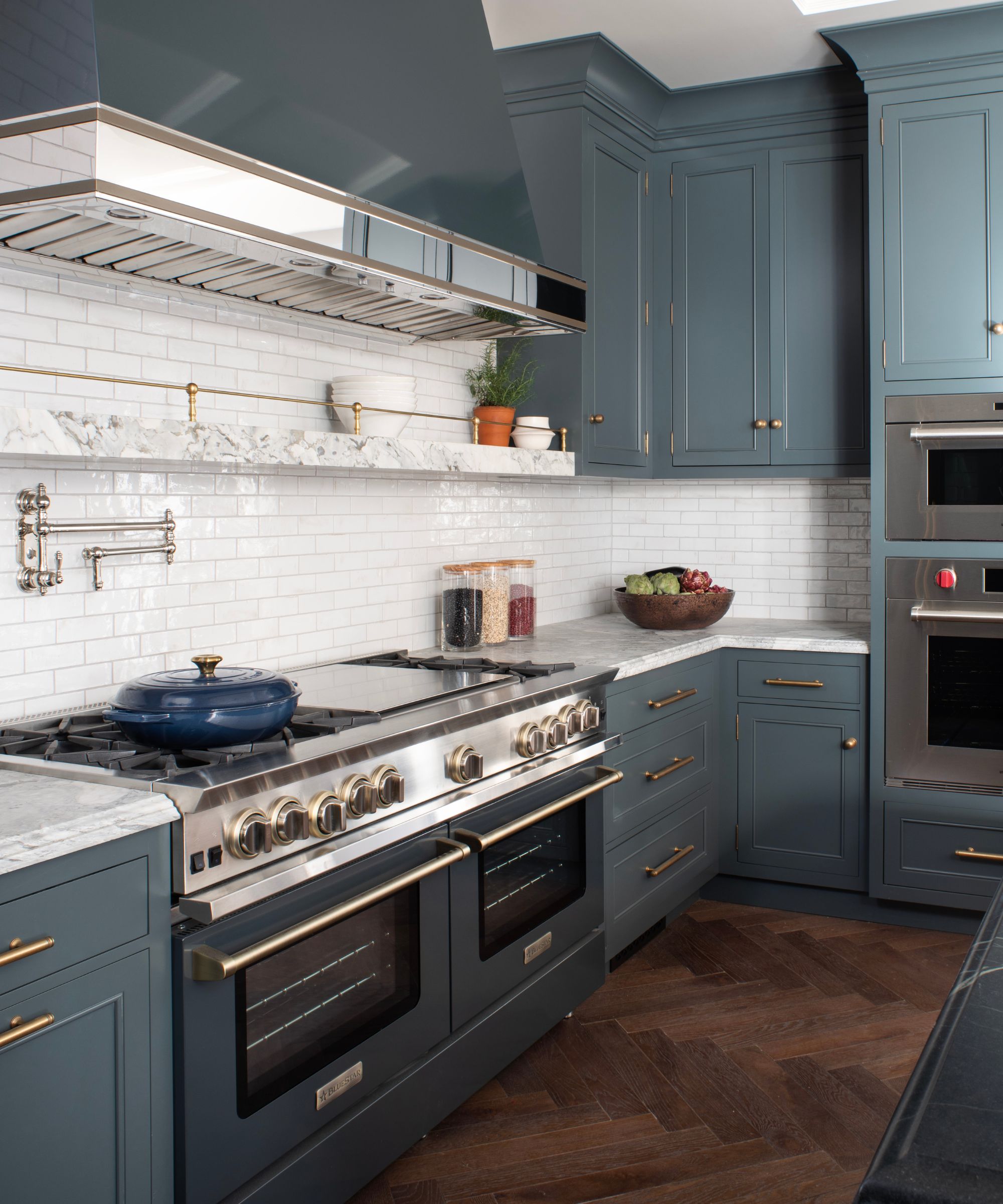 Dark gray kitchen with dark wooden herringbone floors and white marble countertops