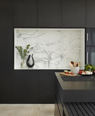 A modern kitchen with a marble backsplash and black cabinets