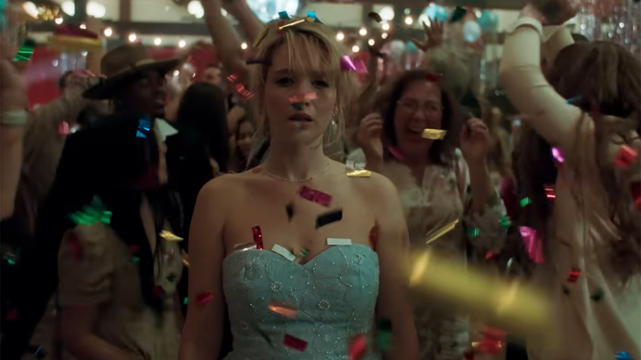 Jennifer Lawrence standing in a blue dress with confetti swirling on Die, My Love.