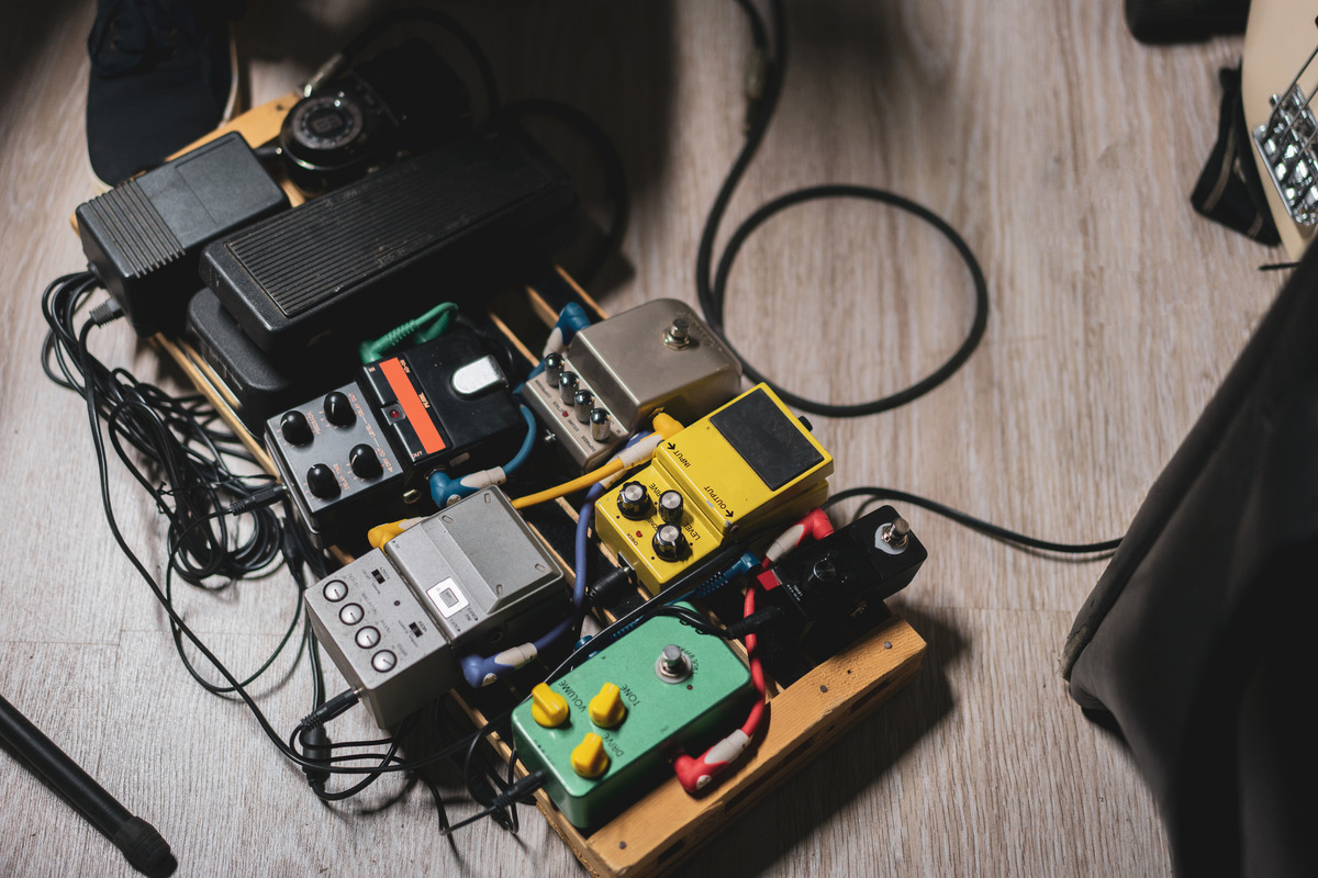 A variety of guitar pedals on a board with cables connecting them all together