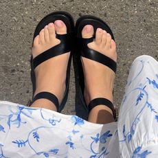 Woman wears black Frankie4 sandals on street with white, blue floral-printed maxi dress.