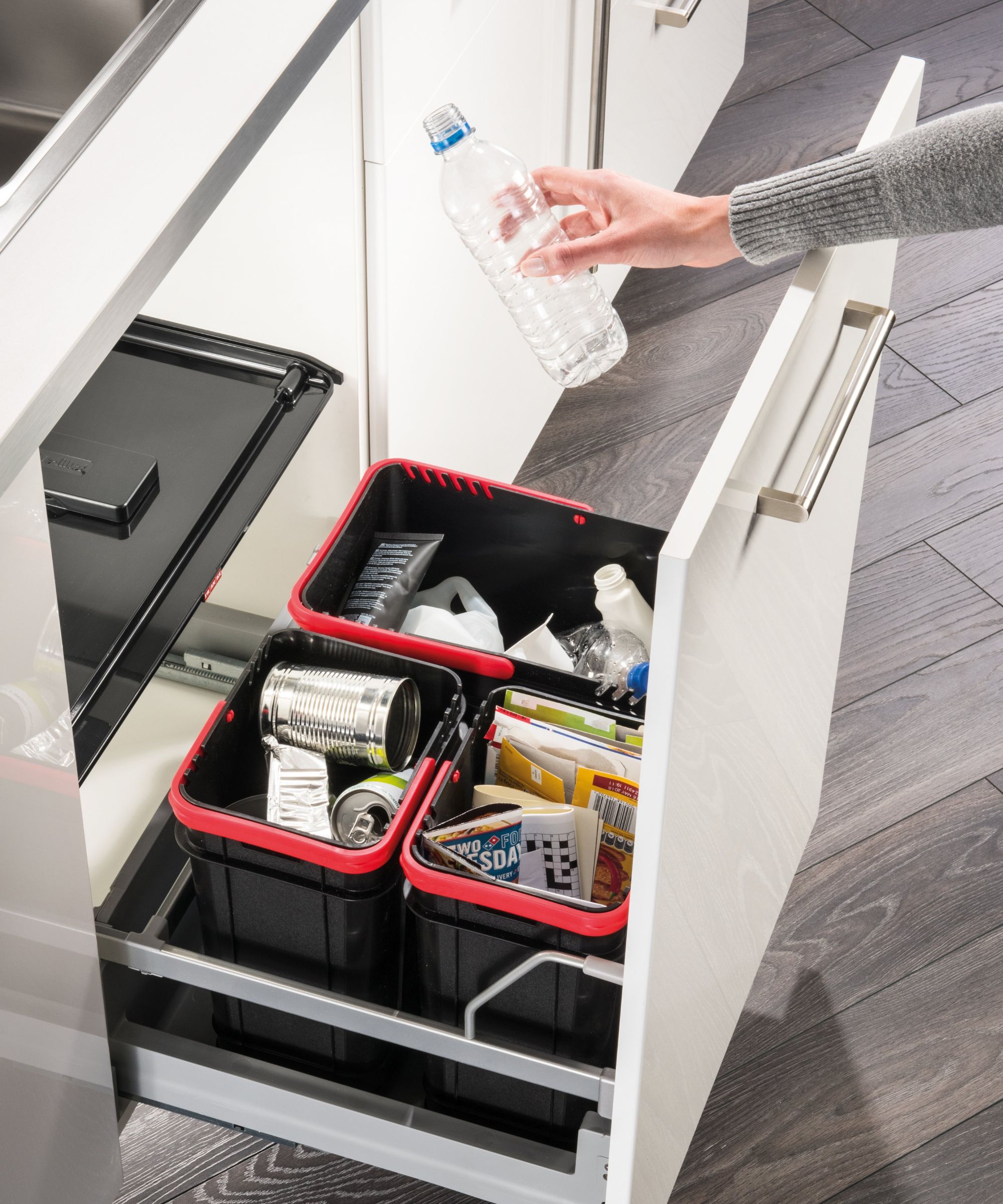 A pull-out kitchen cabinet with multiple recycling bins neatly organised for cans, paper, plastics, and packaging, making waste sorting simple and efficient.