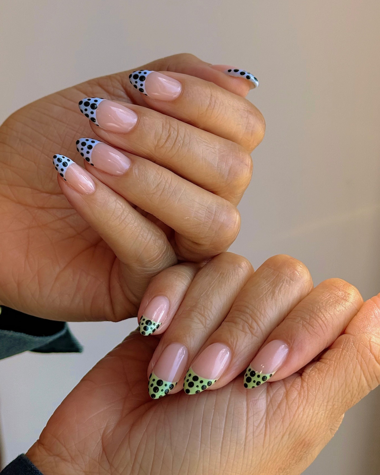 Black and blue dot French tips on one hand, green and black dot French tips on the other