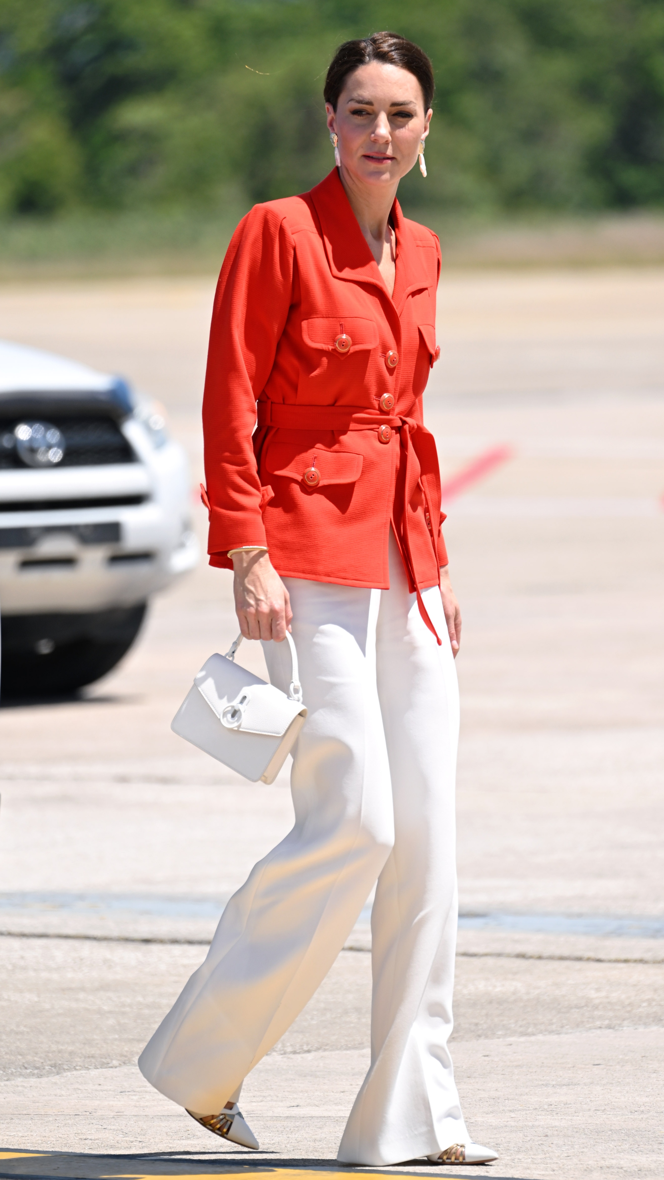 Catherine, Princess of Wales walks, carrying a bag, at Philip S. W Goldson International Airport on March 22, 2022