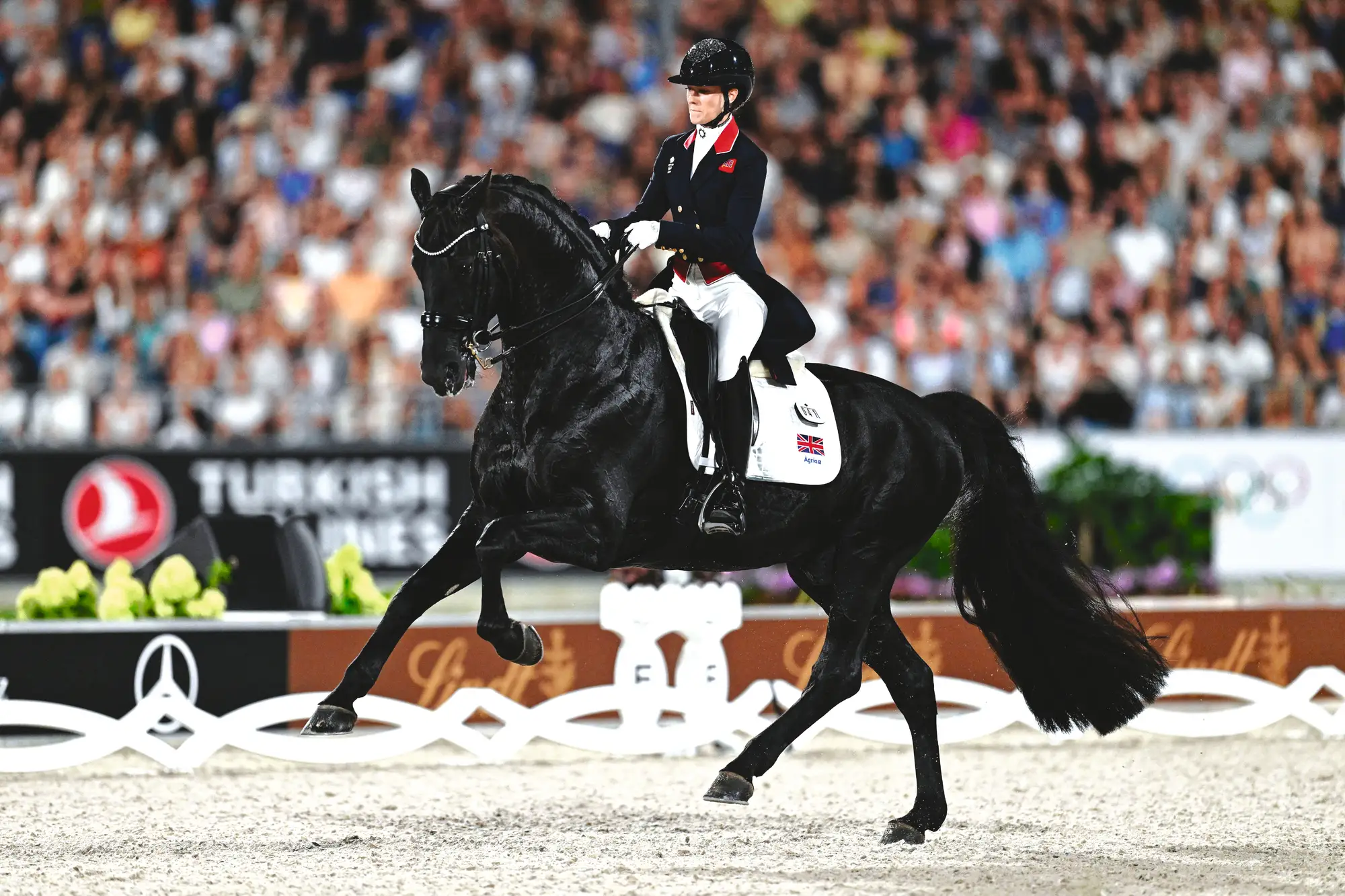 Lottie Fry cantering on Glamourdale in the Aachen dressage arena in front of a crowd