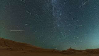 streaks of light cross the starry night sky above a desert