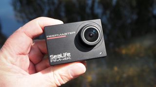 SeaLife ReefMaster RM-4K camera held in a hand outside