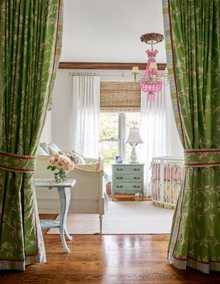 nursery with curtain doorway and polished floor with white crib and day bed and pink chandelier
