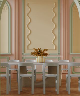 walls painted in pink, yellow and green with wall panelling on different sections in arched and straight sections plus a a wiggly style section on middle panel, pale grey dining table and chairs