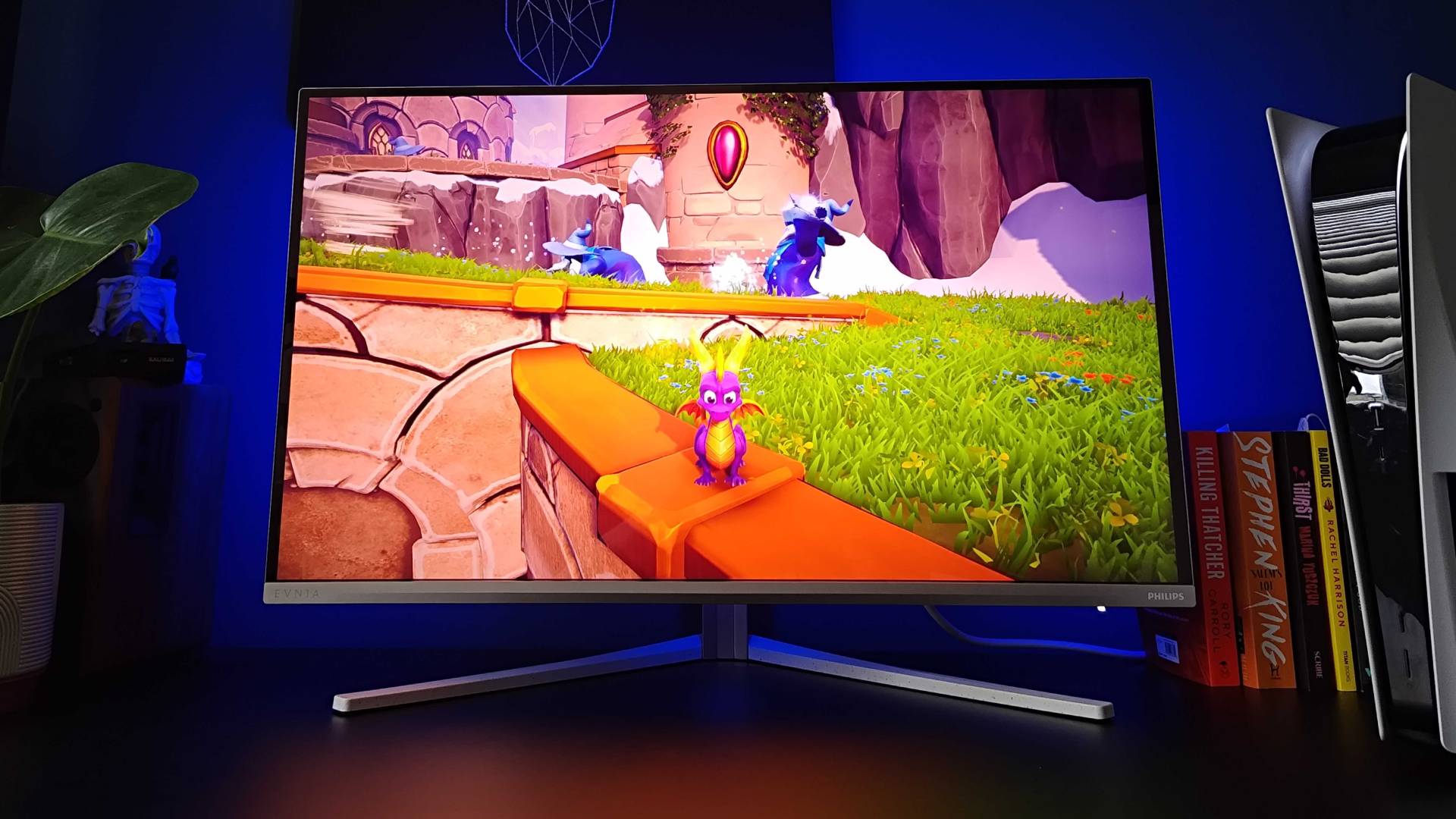 Philips Evnia 32M2N8900 monitor on black desk with Spyro the Dragon standing on ledge.