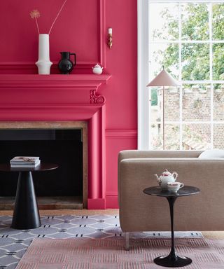 living room with color drenched walls and fireplace, layered rugs, taupe armcahir, white and black vases, black side tables,