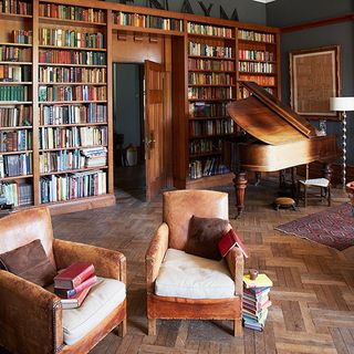 library with wooden book shelve brown armchair and wooden flooring