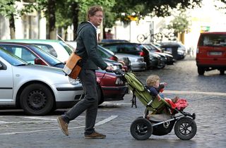 Oliver H., 42, a married federal employee on 6-month paternity leave, pushes his twin 14-month-old daughters Lotte and Alma in a pram while doing errands near his home on August 31, 2010 in Berlin, Germany.