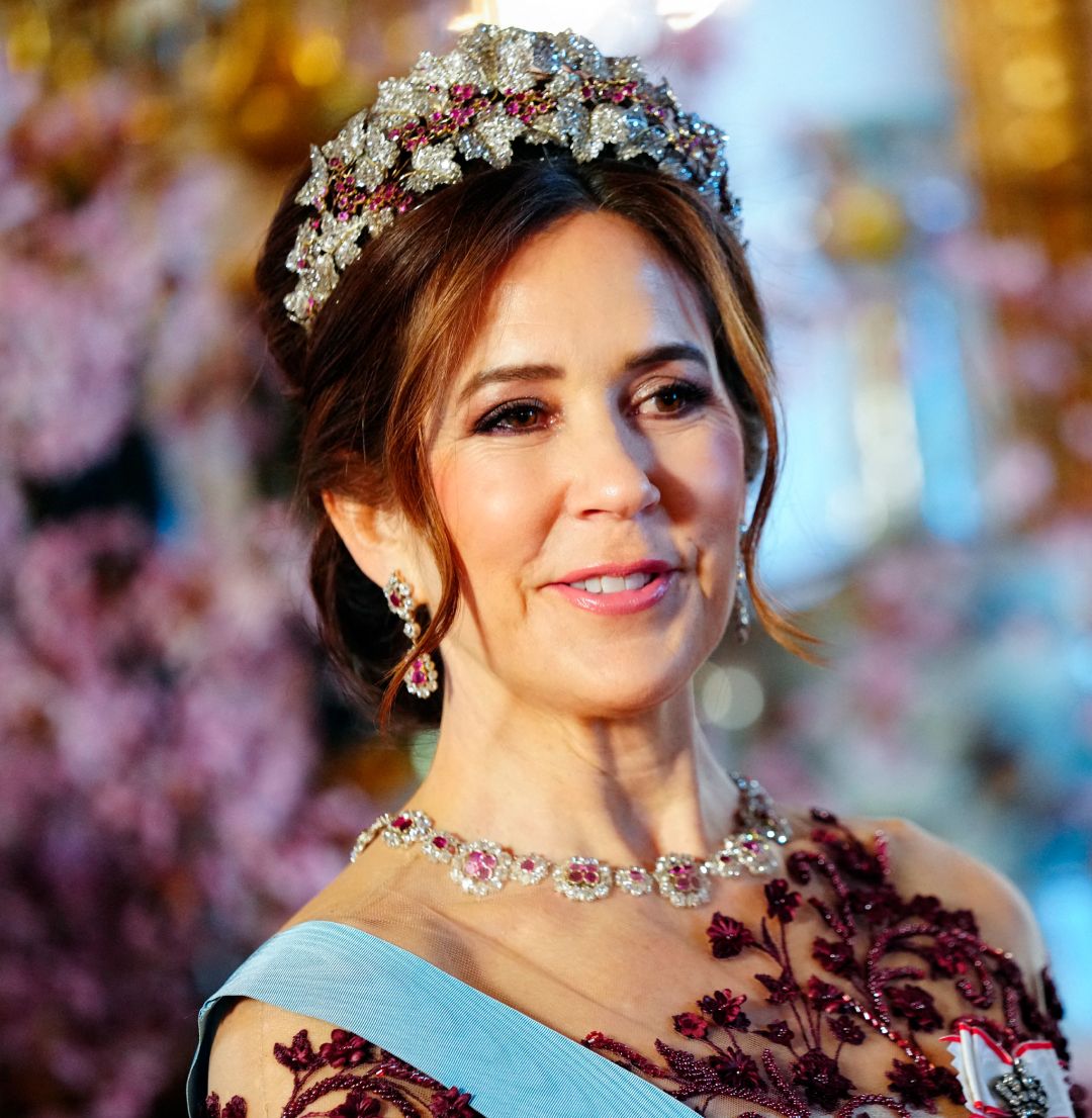 Queen Mary wearing a diamond and ruby tiara and a matching necklace with an embroidered red gown