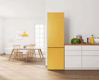 yellow fridge freezer in a white kitchen with wooden floor