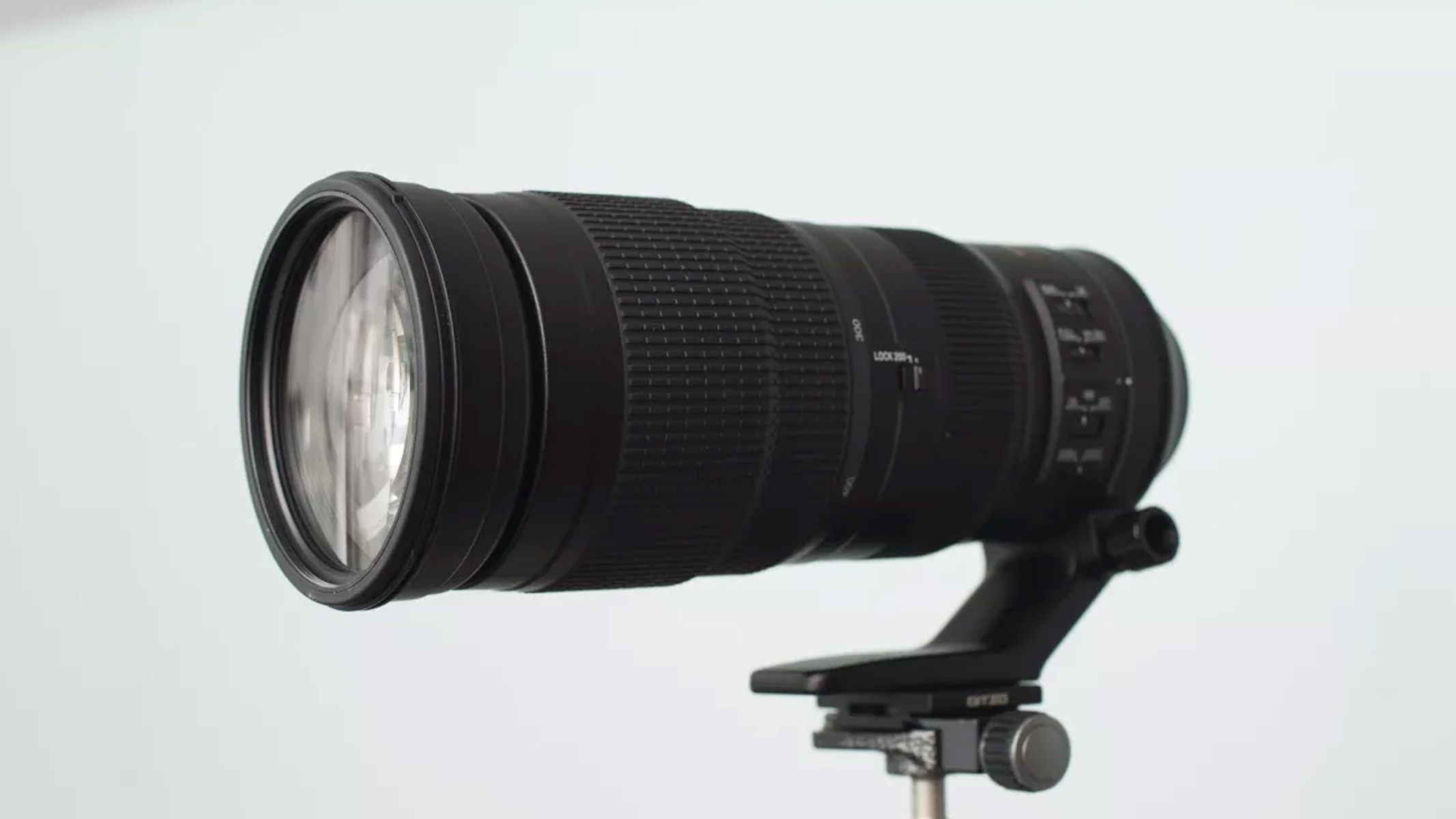 Nikkor AF-S 200-500mm f/5.6E ED VR lens on a tripod with a blue background