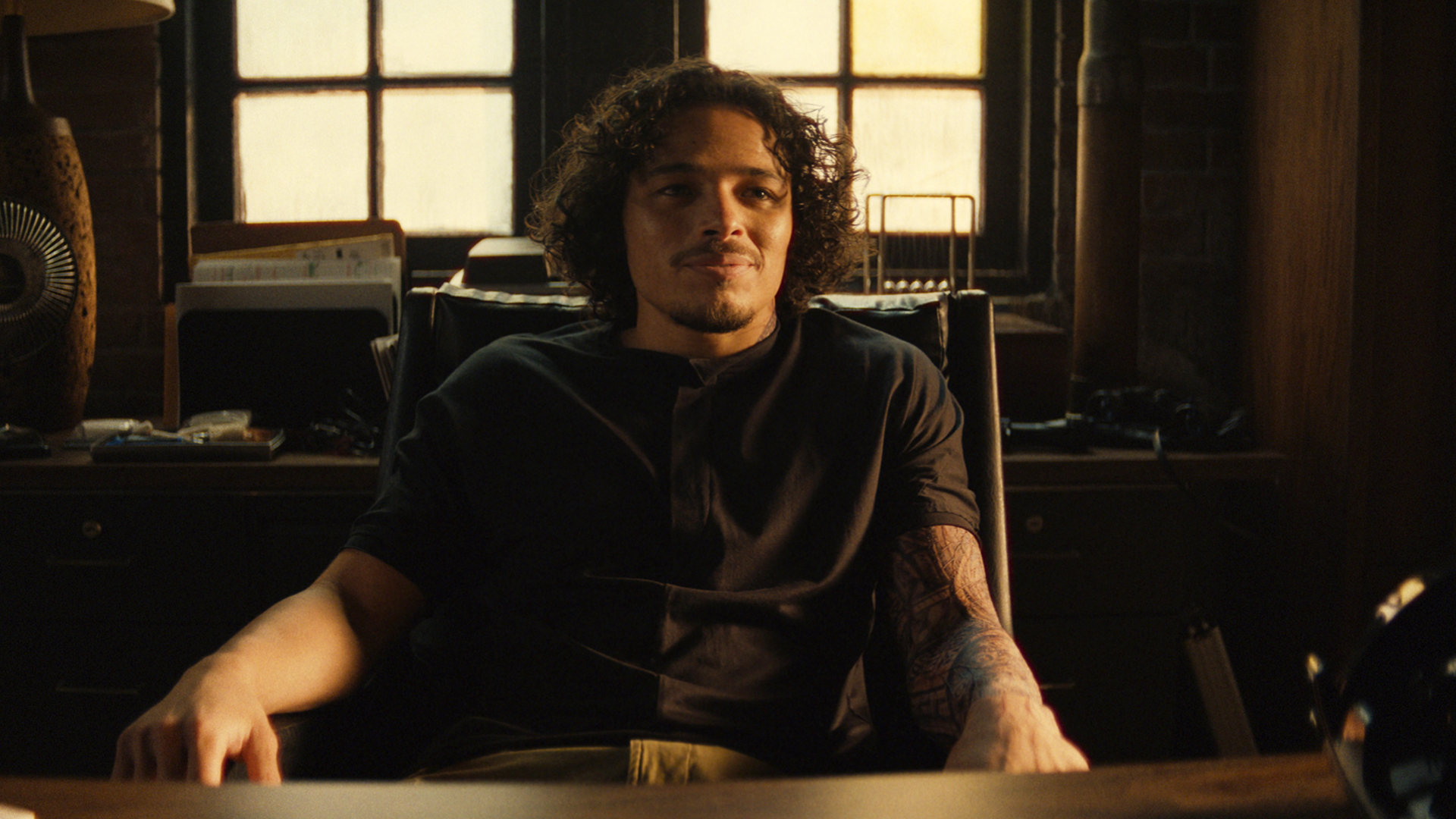 A smiling Parker Robbins sitting at a desk in Ironheart