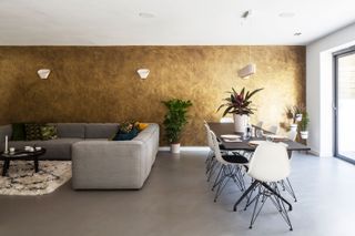 open plan living and dining area with a gold metallic wall