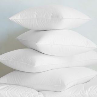 Signature White Down Pillows stacked up against a wall.