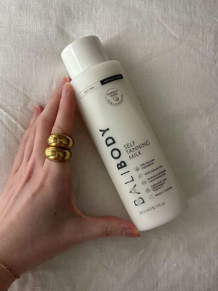 Die stellvertretende Beauty-Redakteurin Grace Lindsay hält die Bali Body Self Tanning Milk in der Hand