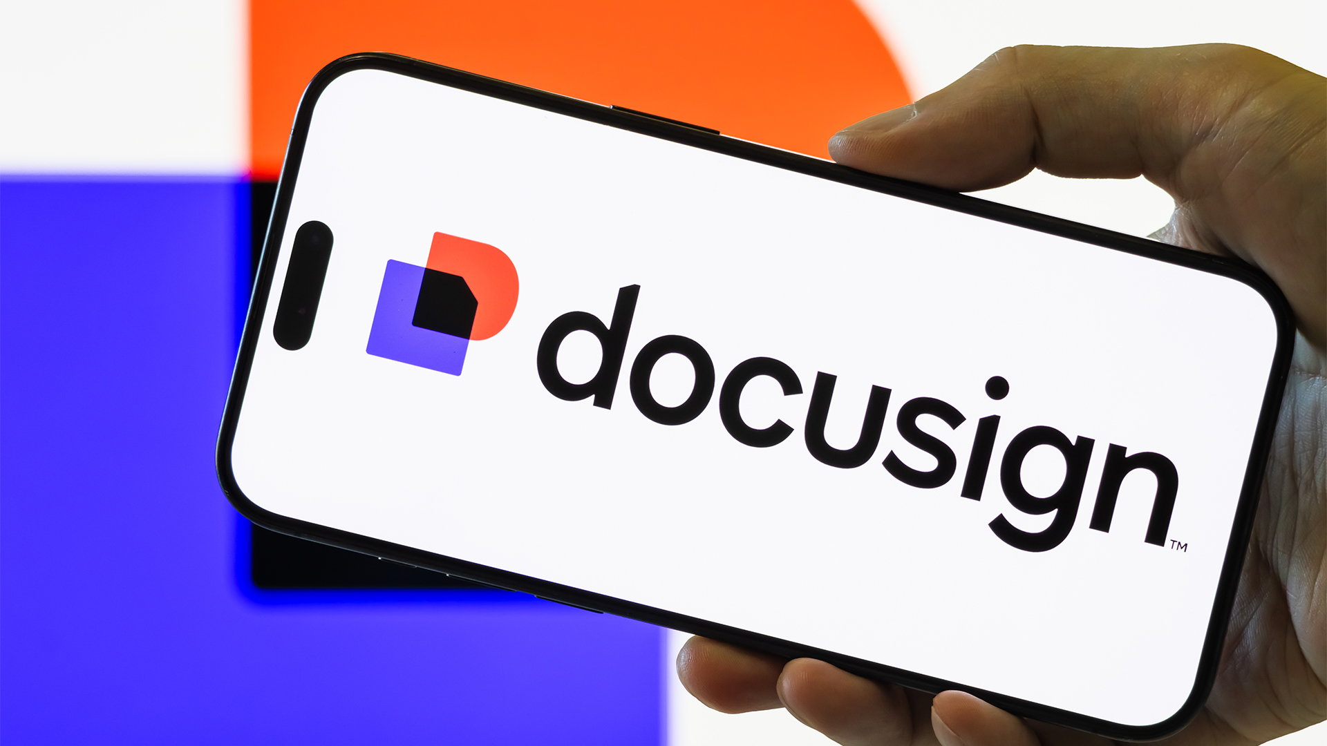 Hand holding up a smartphone with Docusign logo and branding pictured on screen.