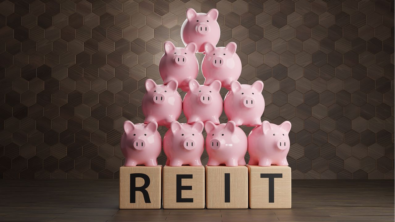 REIT spelled out in wooden blocks with a pyramid of piggy banks on top.