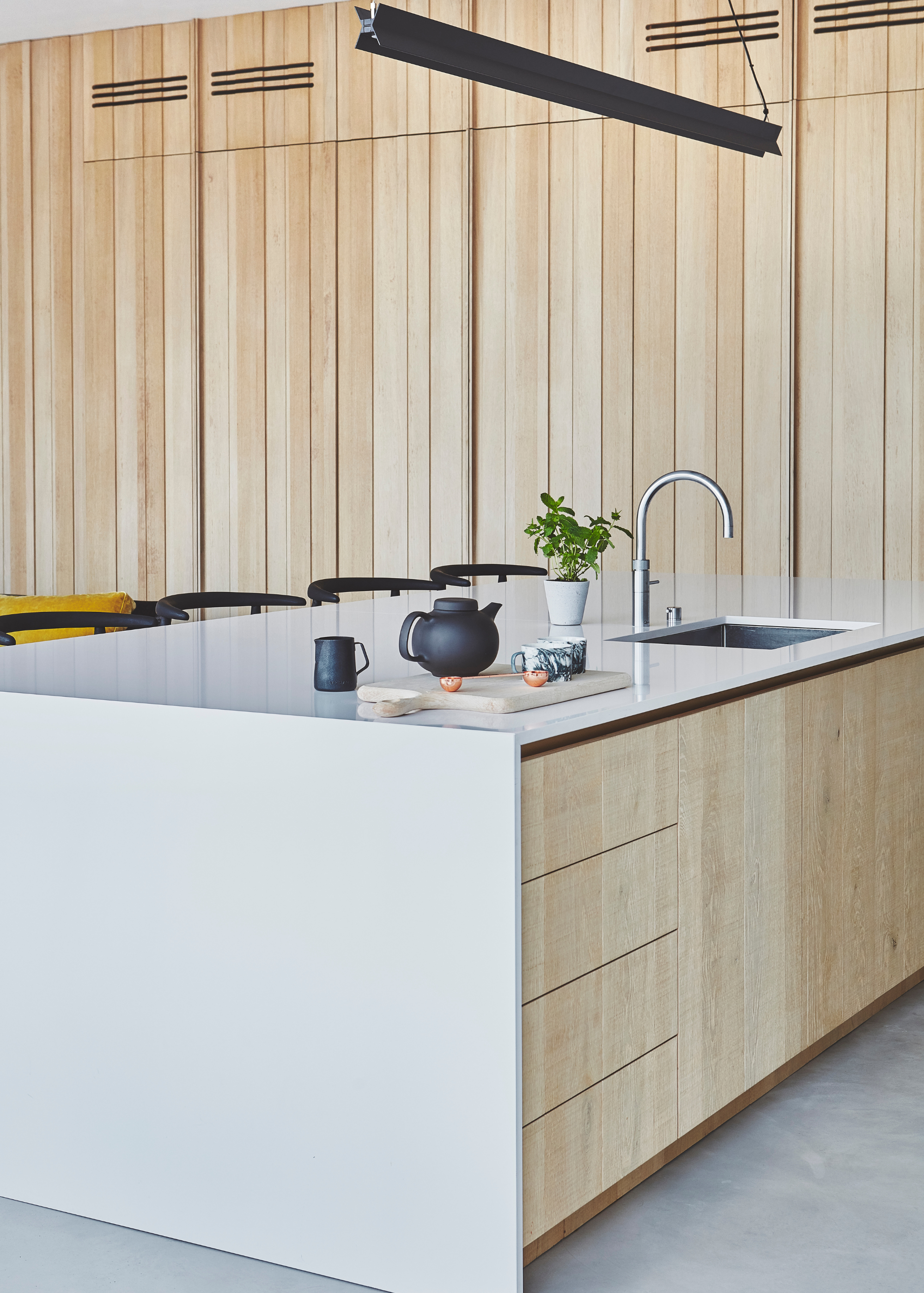HVAC system hidden behind slatted wood cabinets in a modern kitchen with a white kitchen island