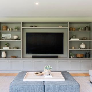 grey wall with grey wall-mounted shelves filled with books and objects