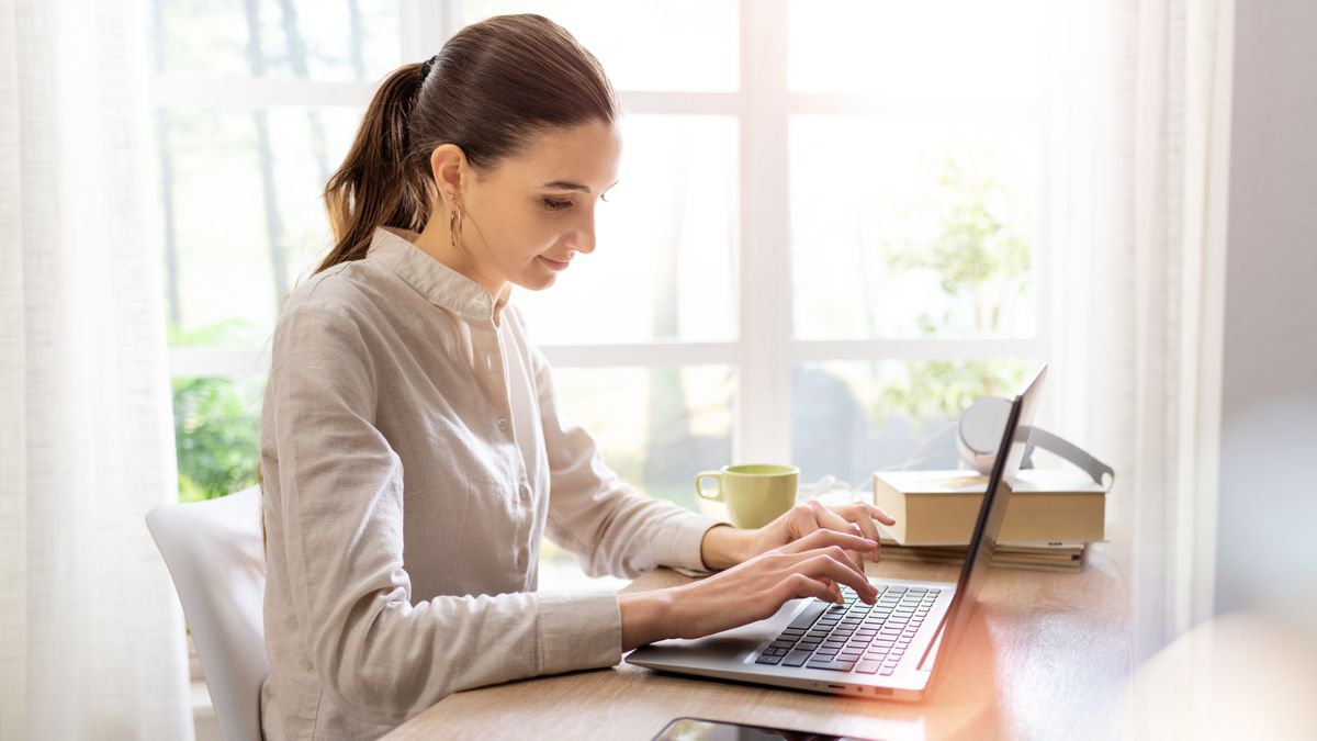 Woman sitting at a desk in her home, working on a laptop 